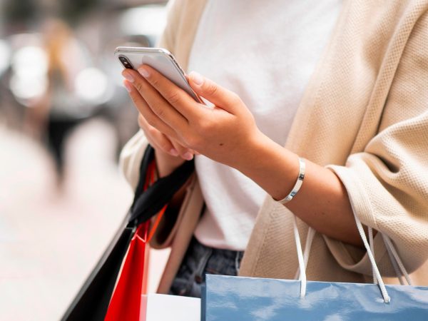 woman-with-shopping-bags-looking-phone-outdoors